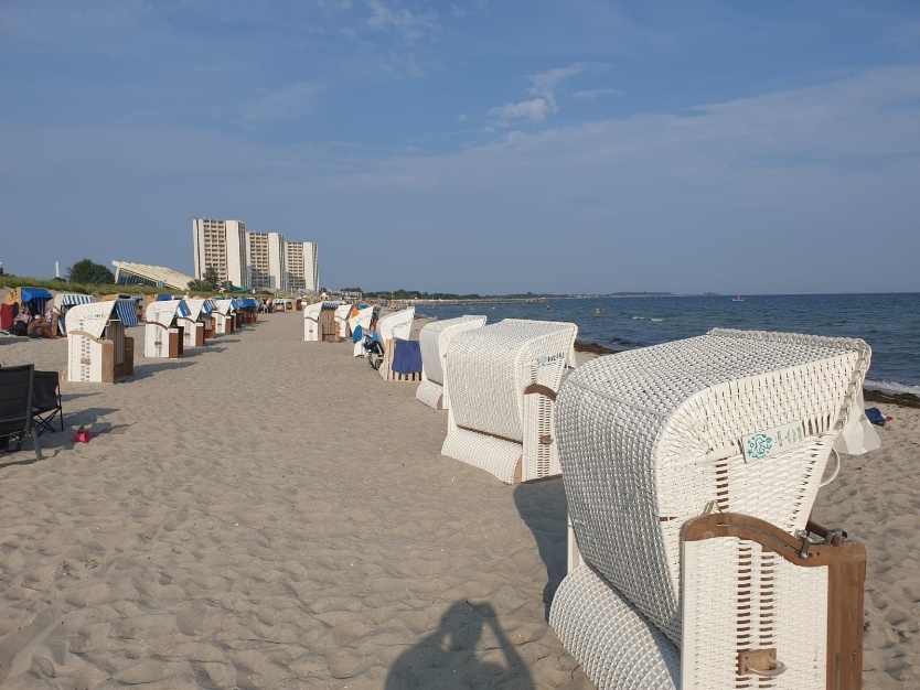 A beach with white chairs and umbrellas

Description automatically generated