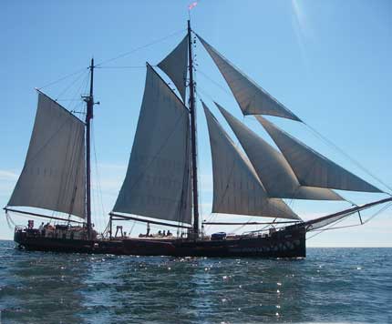 A sailboat with sails on water

Description automatically generated