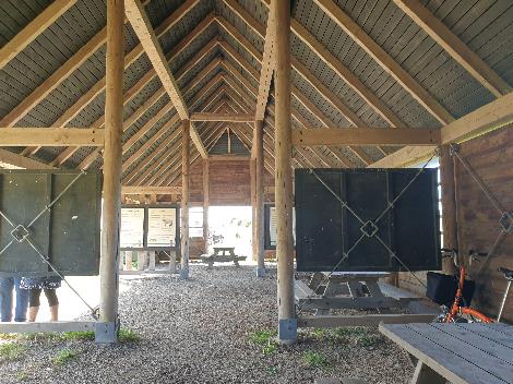 A wooden structure with a bench and tables

Description automatically generated